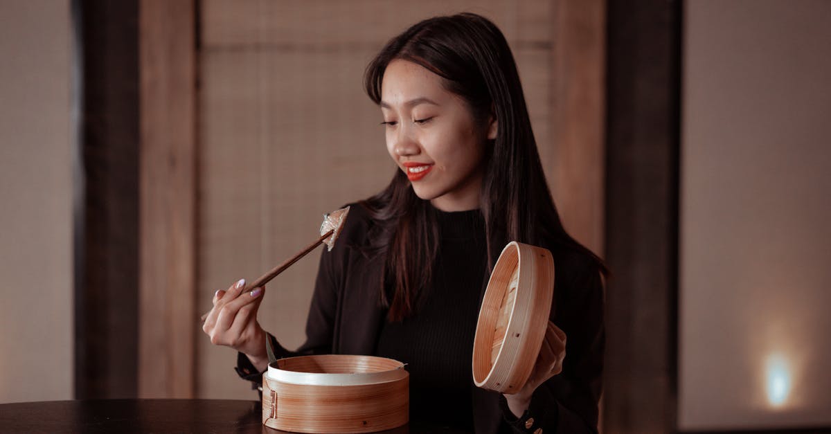 Adding chili powder to a dish makes it dark black - Woman in Black Jacket Holding Chopsticks with Dumplings Adding chili powder to a dish makes it dark black - Woman in Black Jacket Holding Chopsticks with Dumplings