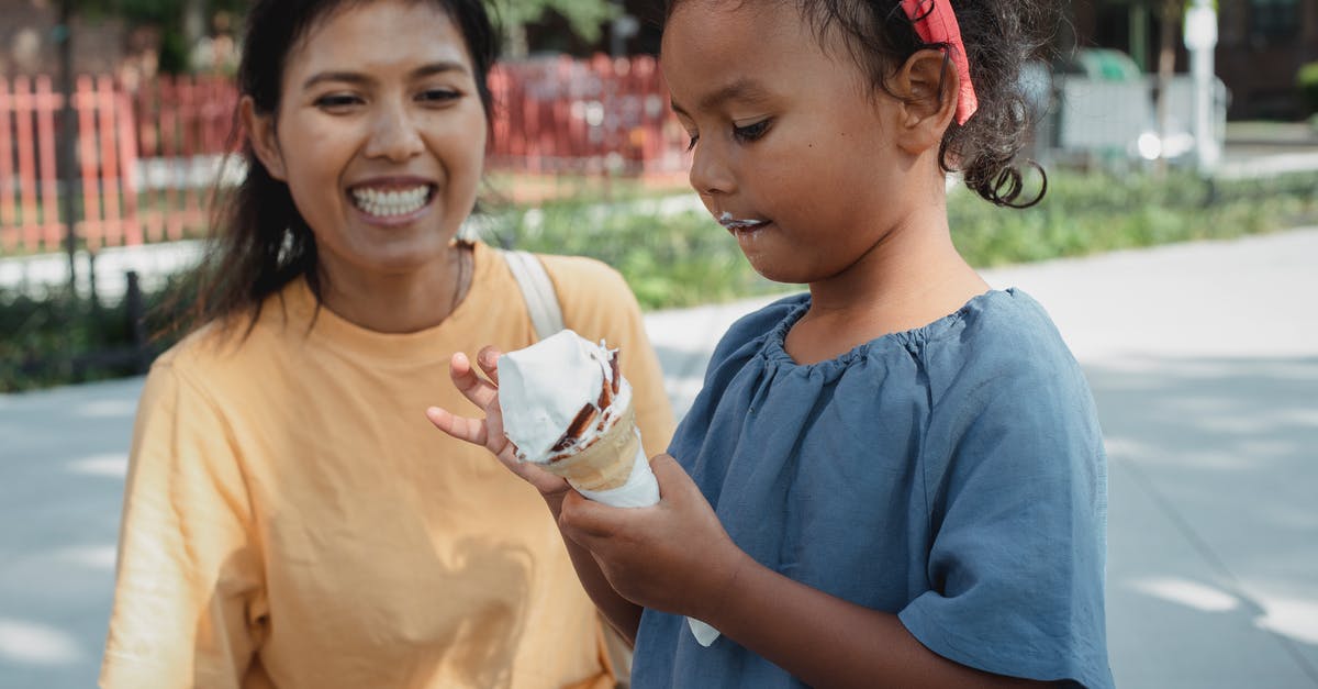 Adding melted butter to cold milk in baking - Cheerful Asian mother looking at daughter eating ice cream Adding melted butter to cold milk in baking - Cheerful Asian mother looking at daughter eating ice cream