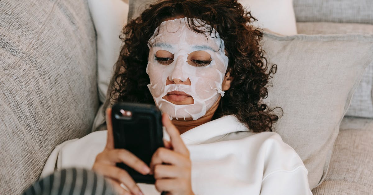 Adding moisture to gluten free muffins - Woman in hydrating sheet mask browsing smartphone Adding moisture to gluten free muffins - Woman in hydrating sheet mask browsing smartphone