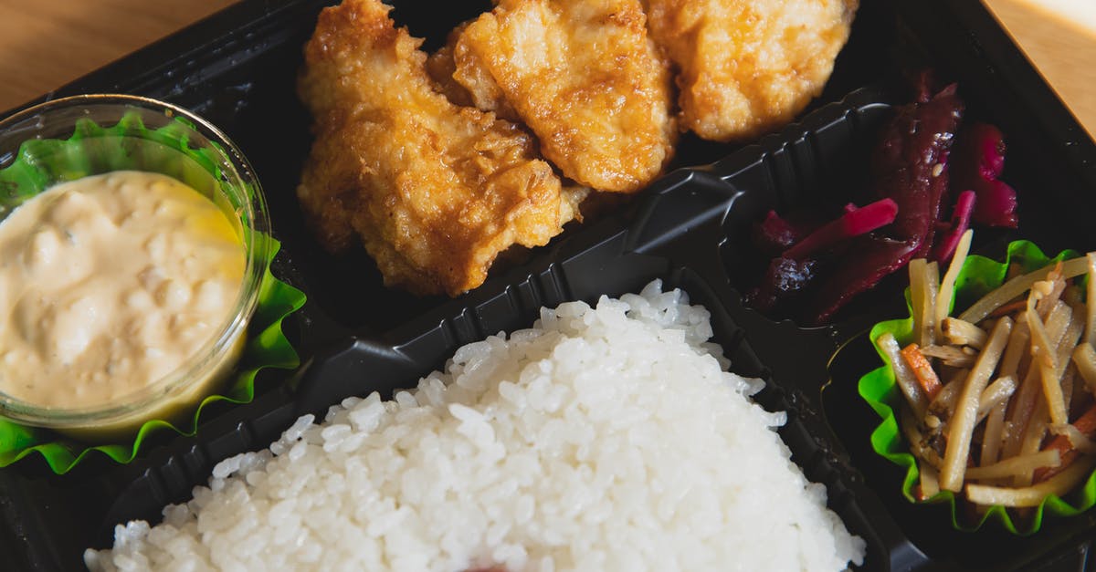 Adding sauce without microwaving the chicken - From above of plastic container with fried chicken and rice with sauce near sauce and sliced vegetables Adding sauce without microwaving the chicken - From above of plastic container with fried chicken and rice with sauce near sauce and sliced vegetables