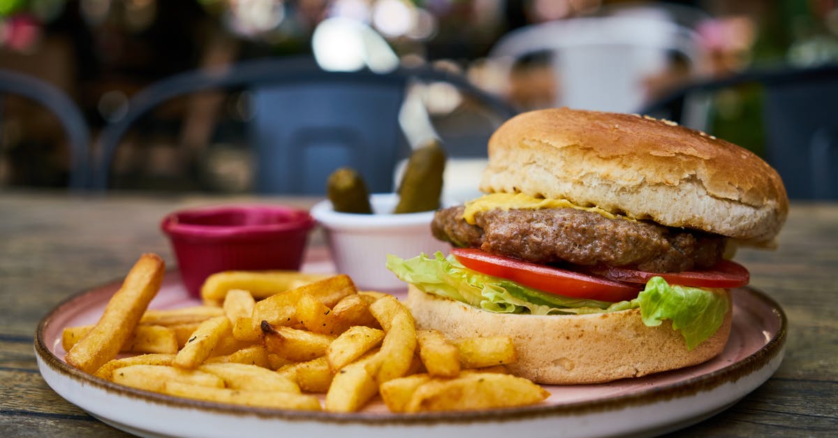 Adding water to a pan-fried burger - Burger and Fries on White Plate Adding water to a pan-fried burger - Burger and Fries on White Plate