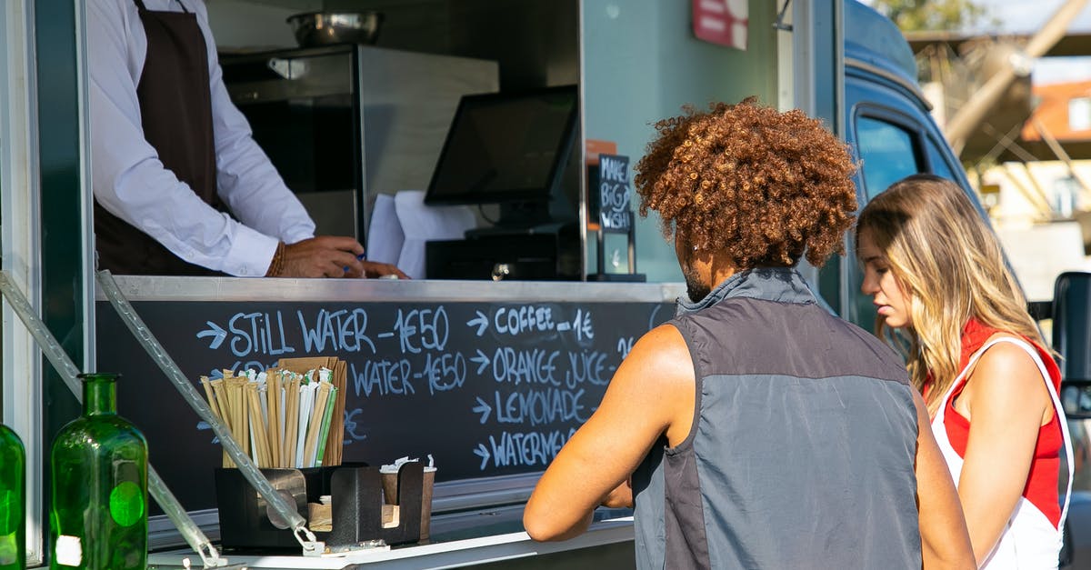 Advice on bulk buying nuts - Multiethnic couple standing together near food truck with seller and selecting dishes from menu in sunny day Advice on bulk buying nuts - Multiethnic couple standing together near food truck with seller and selecting dishes from menu in sunny day