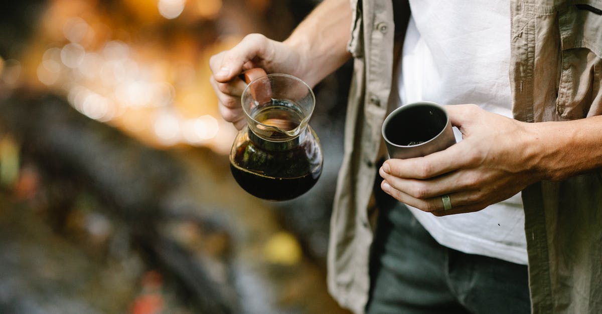 Alternatives to coffee - Crop anonymous male camper pouring freshly brewed coffee from chemex coffeemaker into metal mug while resting in autumn forest during trekking Alternatives to coffee - Crop anonymous male camper pouring freshly brewed coffee from chemex coffeemaker into metal mug while resting in autumn forest during trekking