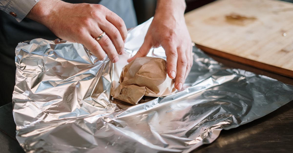 Aluminum foil changed color after wrapping cooked corn - Person in White Long Sleeve Shirt Holding Brown Bread