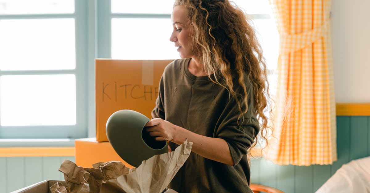 Am I missing out on something by not using parchment paper? - Dreamy female in casual wear taking ceramic vase out of parchment while standing near cardboard box with KITCHEN inscription in back lit preparing to move into new house Am I missing out on something by not using parchment paper? - Dreamy female in casual wear taking ceramic vase out of parchment while standing near cardboard box with KITCHEN inscription in back lit preparing to move into new house