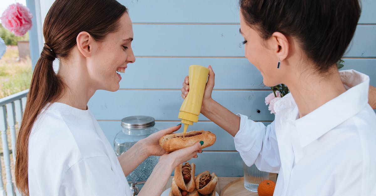 An extensive sausage making site - Women Putting Mustard on Hotdog Sandwich An extensive sausage making site - Women Putting Mustard on Hotdog Sandwich