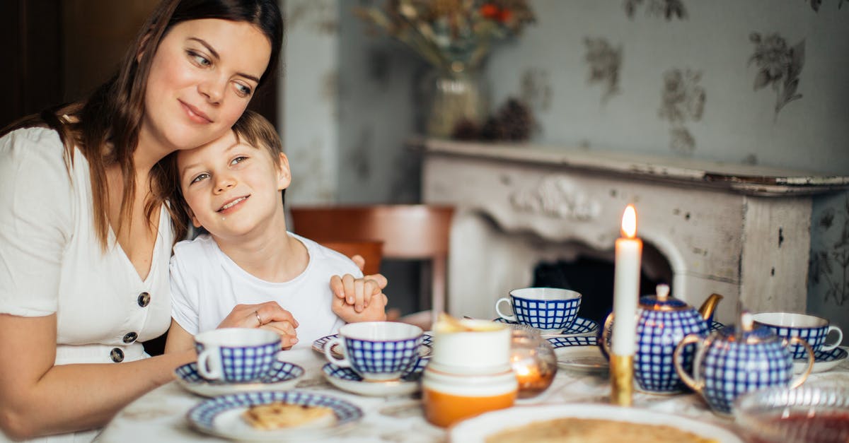 Anise Cookies: Why 12-hour rest before baking? - Cheerful woman cuddling son while sitting in cozy kitchen with candle and blue tea set having crepes and cookies for meal Anise Cookies: Why 12-hour rest before baking? - Cheerful woman cuddling son while sitting in cozy kitchen with candle and blue tea set having crepes and cookies for meal