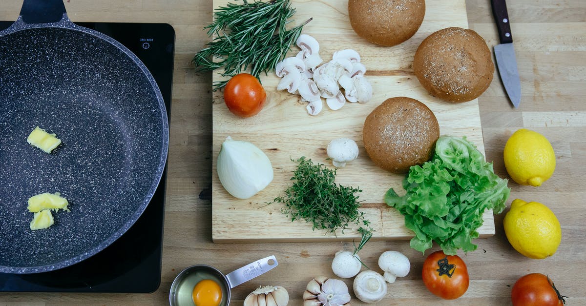 Are garlic butter and garlic oil interchangeable? - Top view of pan with butter on stove placed near wooden board with buns greens and fresh vegetables in kitchen Are garlic butter and garlic oil interchangeable? - Top view of pan with butter on stove placed near wooden board with buns greens and fresh vegetables in kitchen