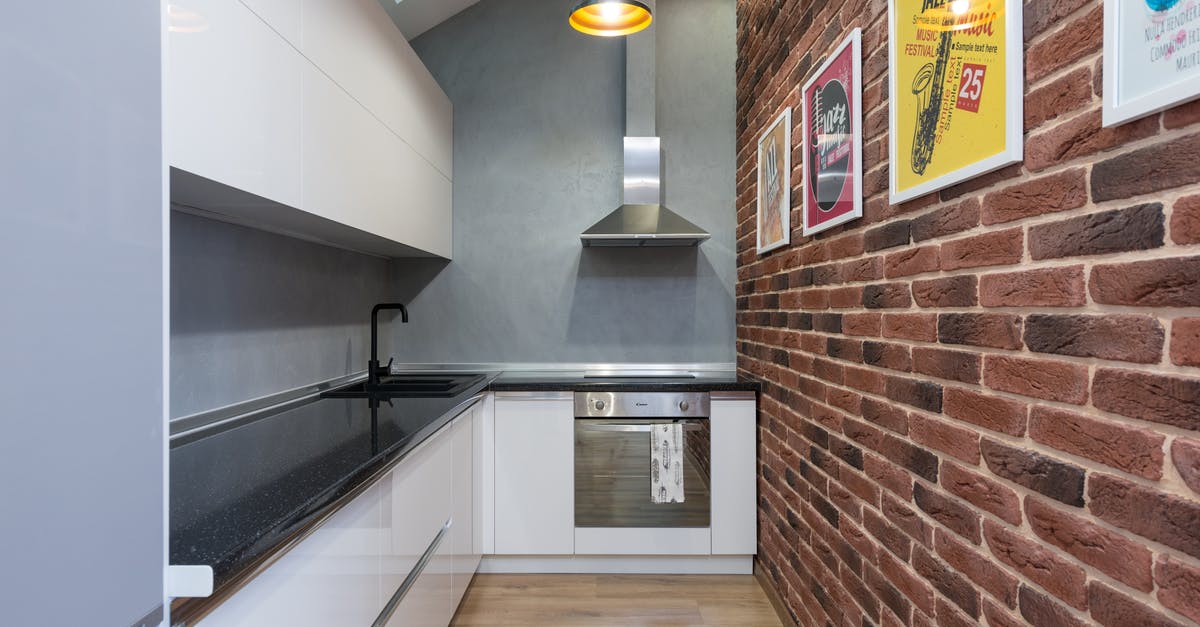 Are recirculation extractor hoods good? - Counter with sink and white cupboards near metal extractor hood and oven in small stylish kitchen with pictures in modern apartment Are recirculation extractor hoods good? - Counter with sink and white cupboards near metal extractor hood and oven in small stylish kitchen with pictures in modern apartment