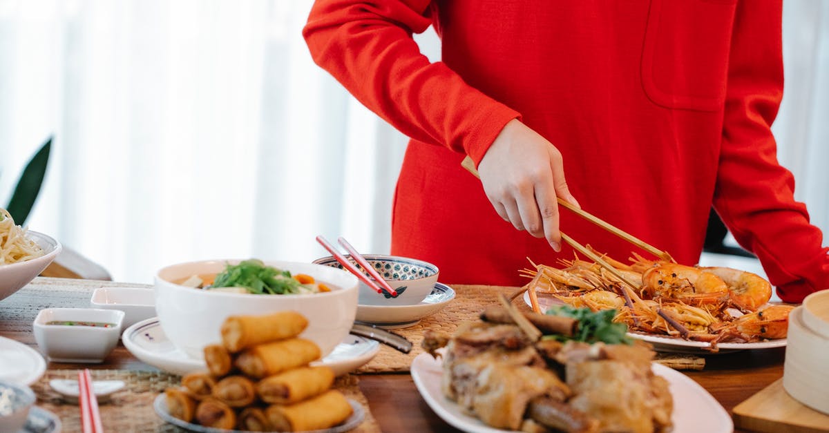 Are the bubbles in the sourdough starter caused by yeast cultures? - Crop unrecognizable female with tweezers serving tasty cooked prawns at table with spring rolls and stewed vegetables at home