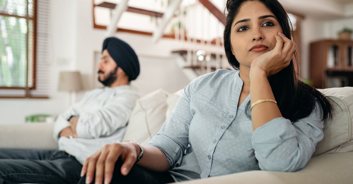 Avoiding foodborne botulism - Sad young Indian woman avoiding talking to husband while sitting on sofa Avoiding foodborne botulism - Sad young Indian woman avoiding talking to husband while sitting on sofa