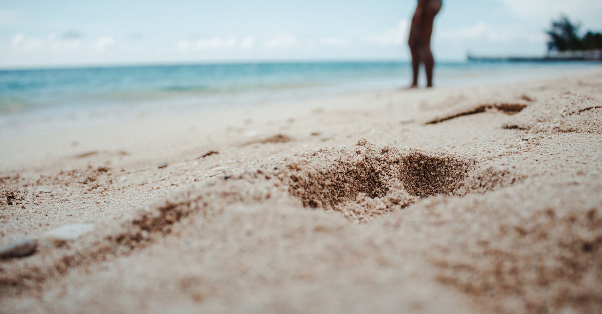 Baking below sea level - Crop female traveler on sandy sea shore with holes Baking below sea level - Crop female traveler on sandy sea shore with holes