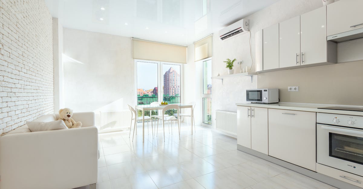 Baking cakes in the Microwave ovens as compared to Electric ovens - Interior of modern house with wooden table and chairs placed near kitchen with white cabinets and appliances Baking cakes in the Microwave ovens as compared to Electric ovens - Interior of modern house with wooden table and chairs placed near kitchen with white cabinets and appliances