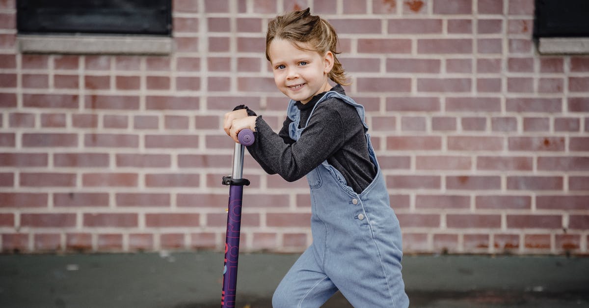 Balance overly sweet liqueurs - Side view of happy little girl in denim outfit smiling while riding scooter and looking at camera Balance overly sweet liqueurs - Side view of happy little girl in denim outfit smiling while riding scooter and looking at camera