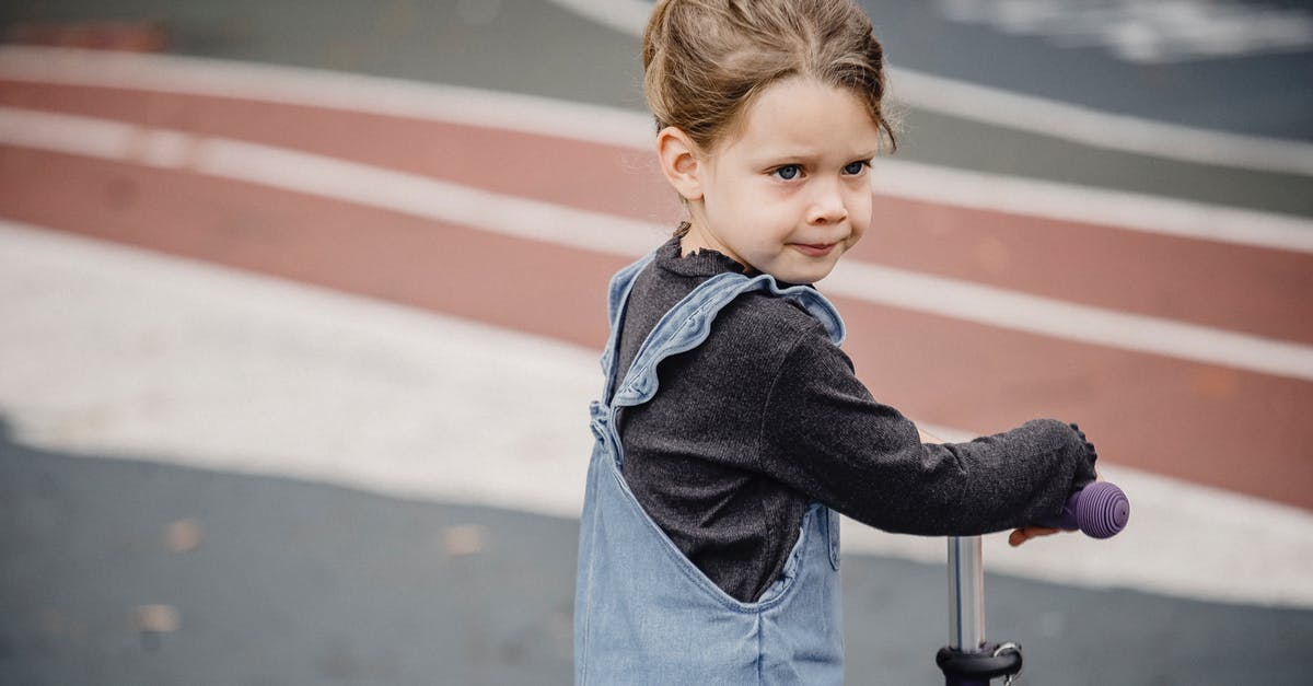 Balance overly sweet liqueurs - Side view of adorable preschool girl in casual clothes riding scooter on asphalt ground and looking away Balance overly sweet liqueurs - Side view of adorable preschool girl in casual clothes riding scooter on asphalt ground and looking away