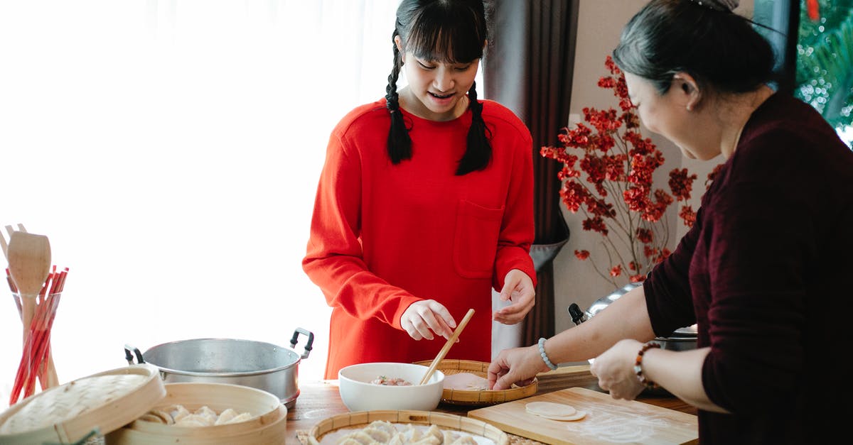 Bamboo Steamer VS Normal Steamer - Smiling ethnic grandma with female teen preparing Chinese dumplings while talking at table with traditional steamers in house Bamboo Steamer VS Normal Steamer - Smiling ethnic grandma with female teen preparing Chinese dumplings while talking at table with traditional steamers in house
