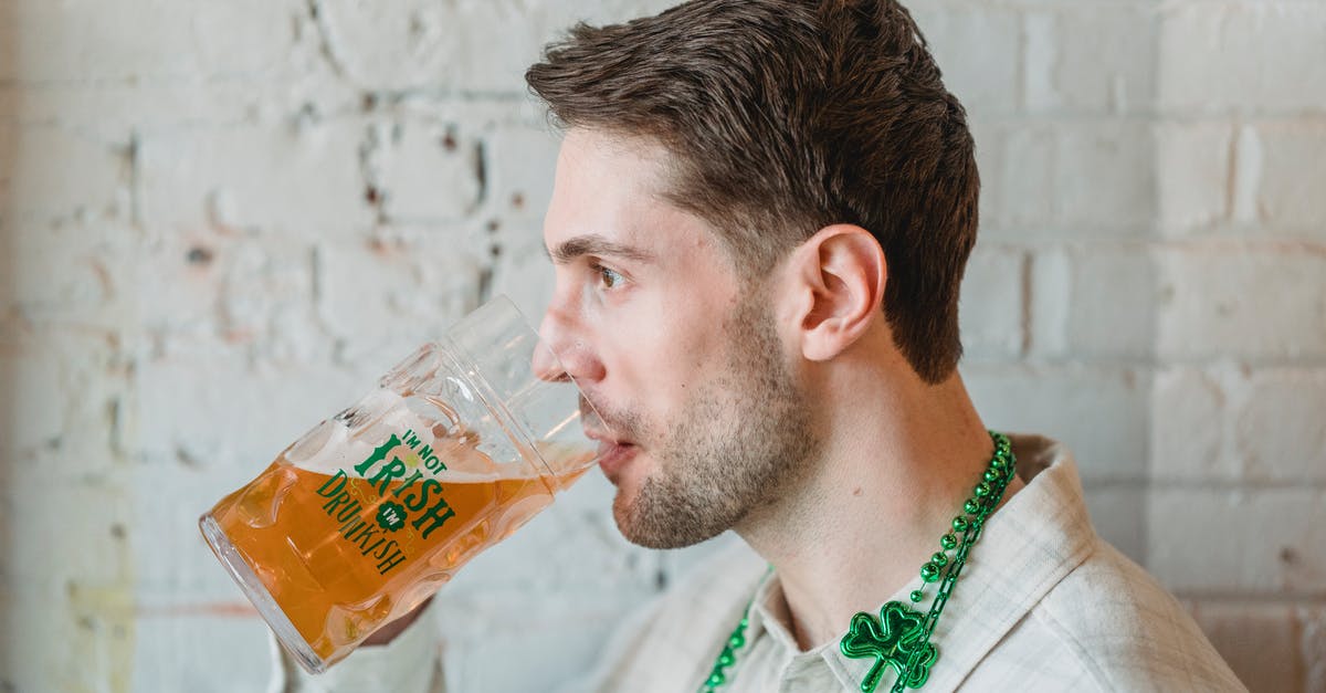 Beer Battered Onion Rings -- what makes them look shiny? - Side view of young male drinking glass of beer on festive event near white brick wall Beer Battered Onion Rings -- what makes them look shiny? - Side view of young male drinking glass of beer on festive event near white brick wall