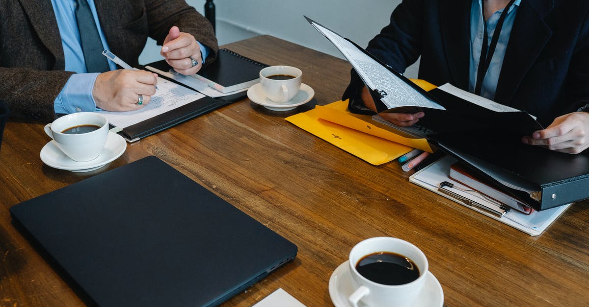 Best Office Coffee Solution [closed] - Crop unrecognizable coworkers in formal clothes sitting at table with documents and cups of coffee while working together