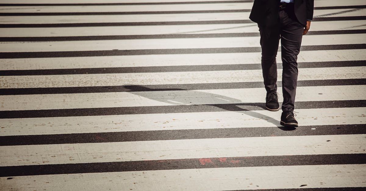 Best practices for using taps while avoiding cross contamination - Faceless businessman with smartphone walking on crosswalk in sunlight Best practices for using taps while avoiding cross contamination - Faceless businessman with smartphone walking on crosswalk in sunlight
