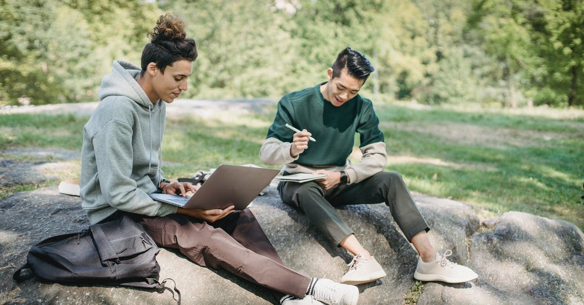 Best way to reheat pizza - Full length young men friends in casual outfit sitting on big boulder with computer while writing notes with pen in notepad in summer sunny day with trees on background Best way to reheat pizza - Full length young men friends in casual outfit sitting on big boulder with computer while writing notes with pen in notepad in summer sunny day with trees on background