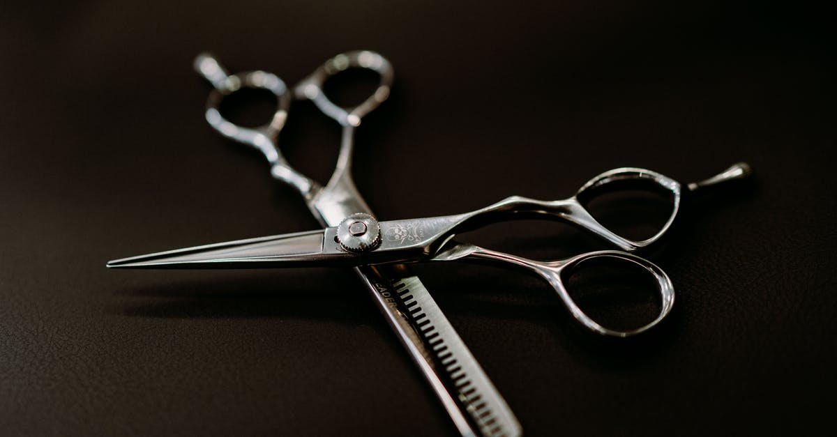 Black flakes from new cast iron pan - From above of shiny steel scissors for hairdresser on black background of studio Black flakes from new cast iron pan - From above of shiny steel scissors for hairdresser on black background of studio