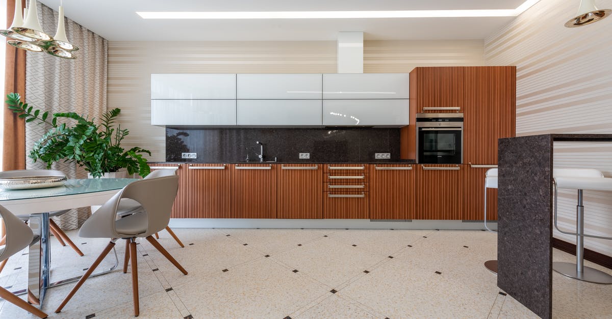 Black spots in the kitchen sink - Contemporary kitchen with modern appliance and black counter with wooden cupboards placed near table with chairs and green potted plant on tiled floor Black spots in the kitchen sink - Contemporary kitchen with modern appliance and black counter with wooden cupboards placed near table with chairs and green potted plant on tiled floor