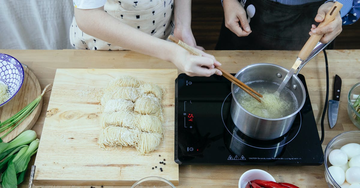 Boil an egg in the microwave - Crop anonymous housewives in aprons boiling noodles on tabletop stove near fresh ingredients in modern kitchen Boil an egg in the microwave - Crop anonymous housewives in aprons boiling noodles on tabletop stove near fresh ingredients in modern kitchen