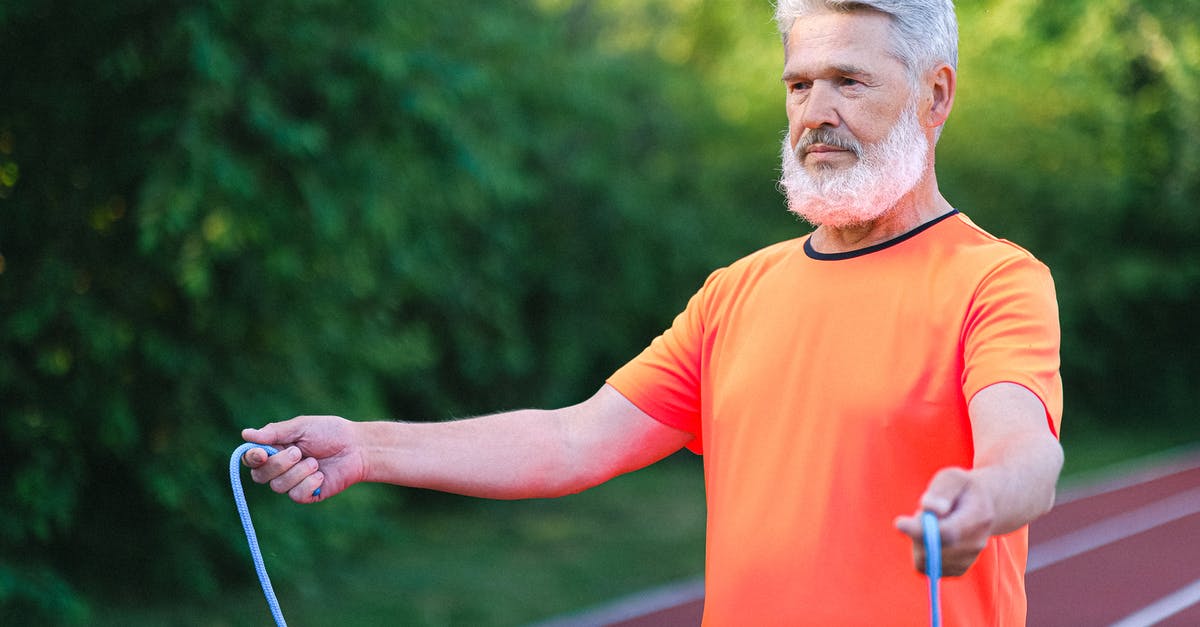Bread with strong vinegar smell - Focused elderly man with bread in sportswear standing wit jump rope on stadium and looking forward Bread with strong vinegar smell - Focused elderly man with bread in sportswear standing wit jump rope on stadium and looking forward