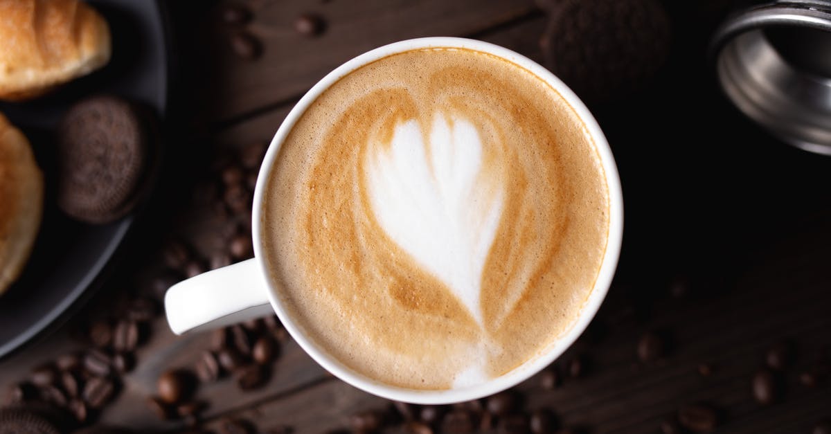 breaking off chocolate from a block of chocolate - Top view composition of freshly brewed cappuccino served on dark table and surrounded by coffee beans and chocolate cookies