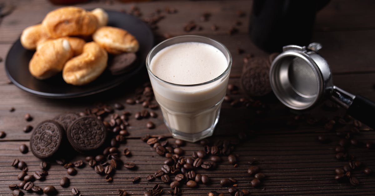 breaking off chocolate from a block of chocolate - Glass of milk on table near pastries and coffee beans