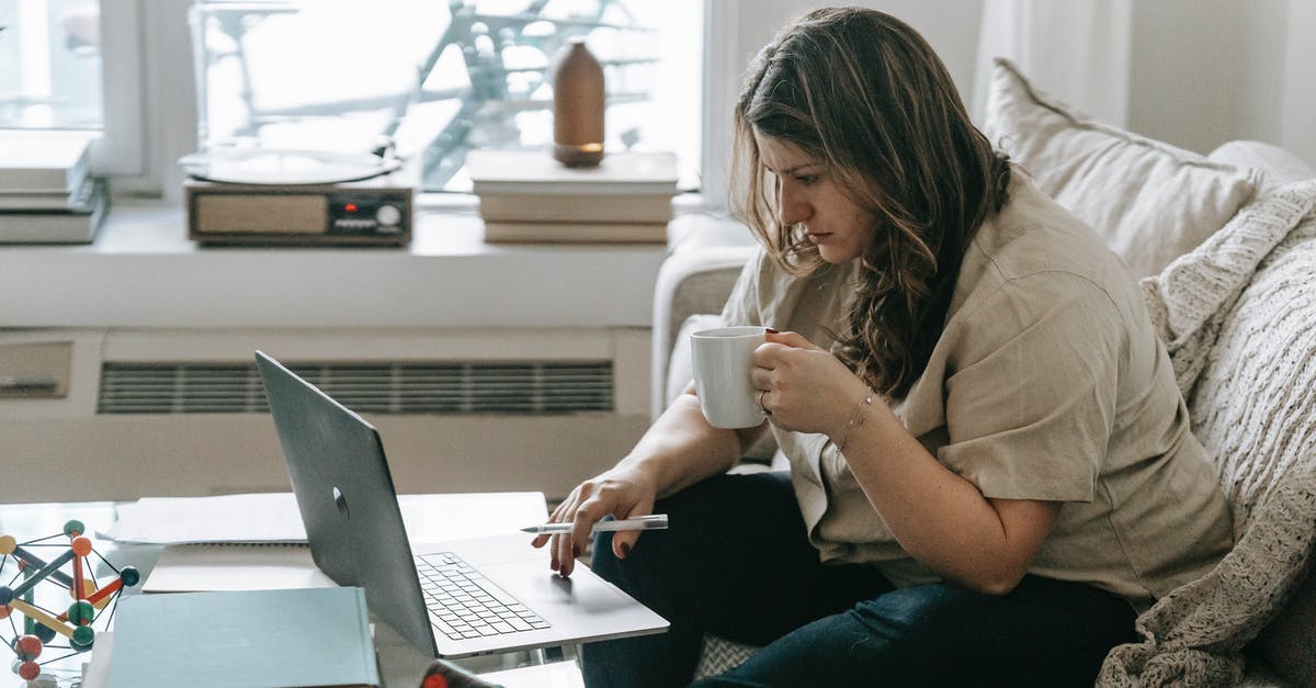 Brewing coffee concentrate using both hot and cold methods - Freezing concentrate - Woman with cup sitting on couch while working on laptop Brewing coffee concentrate using both hot and cold methods - Freezing concentrate - Woman with cup sitting on couch while working on laptop