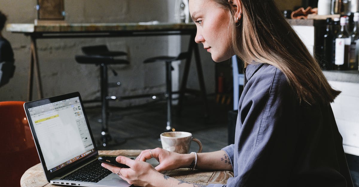 Brewing coffee concentrate using both hot and cold methods - Freezing concentrate - Side view of young focused woman browsing laptop sitting at table with cup of hot beverage in cafe Brewing coffee concentrate using both hot and cold methods - Freezing concentrate - Side view of young focused woman browsing laptop sitting at table with cup of hot beverage in cafe