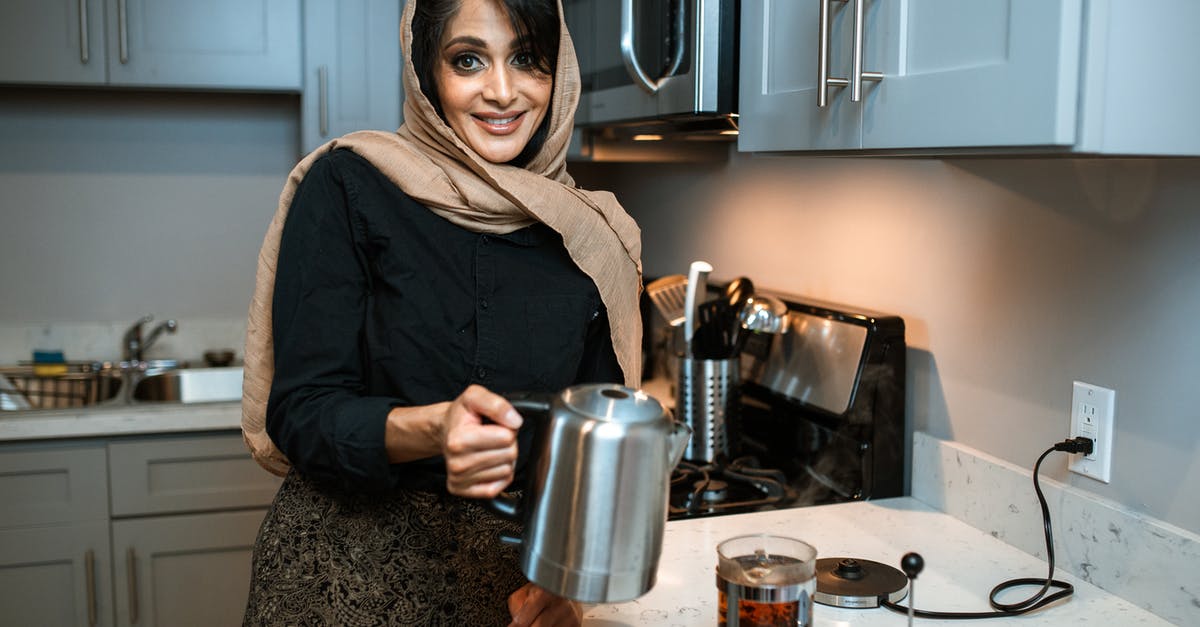 Brewing Hibiscus tea - 
A Woman Holding a Silver Kettle
