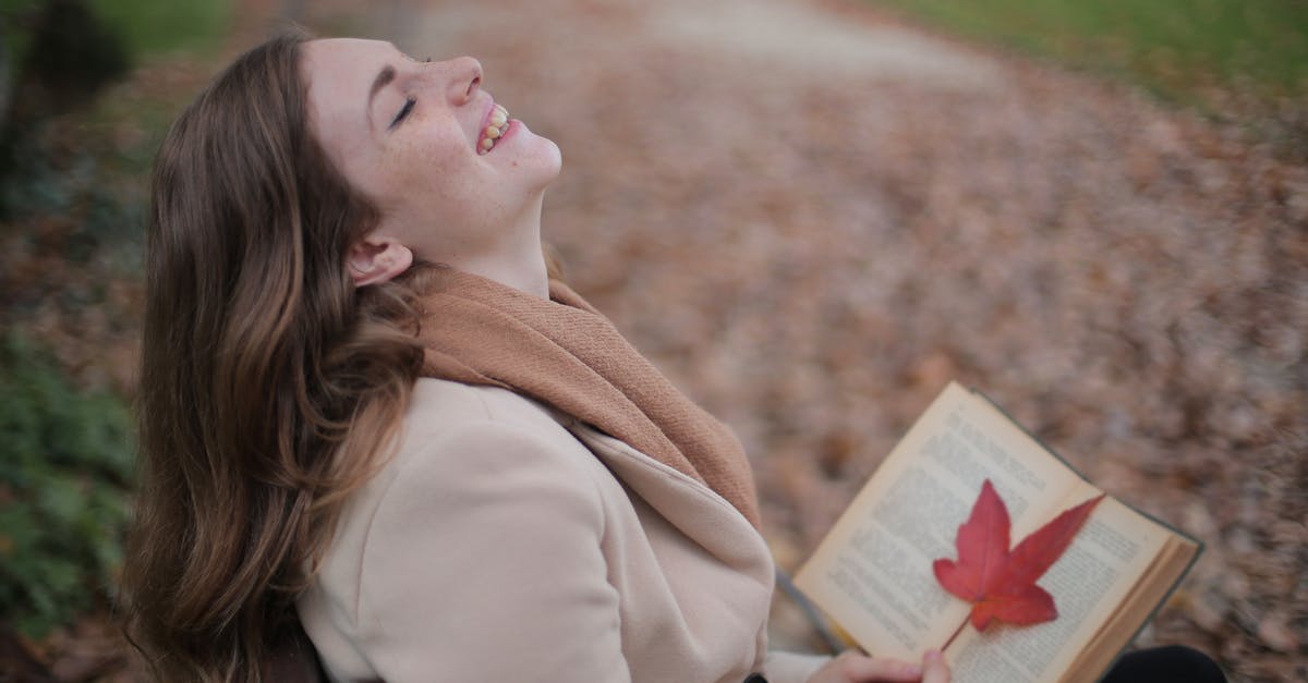 Brown Blob in natural maple syrup? - Cheerful young woman with red leaf enjoying life and weather while reading book in autumn park Brown Blob in natural maple syrup? - Cheerful young woman with red leaf enjoying life and weather while reading book in autumn park