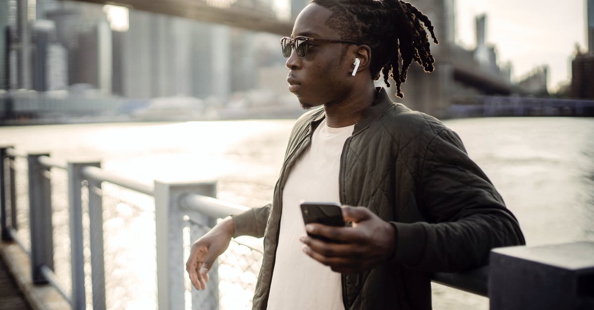 Burned water out of pot...popping sound a month later? - Thoughtful masculine African American guy in sunglasses and true wireless earphones listening to music from cellphone while standing leaned on bridge fence passing over city river Burned water out of pot...popping sound a month later? - Thoughtful masculine African American guy in sunglasses and true wireless earphones listening to music from cellphone while standing leaned on bridge fence passing over city river