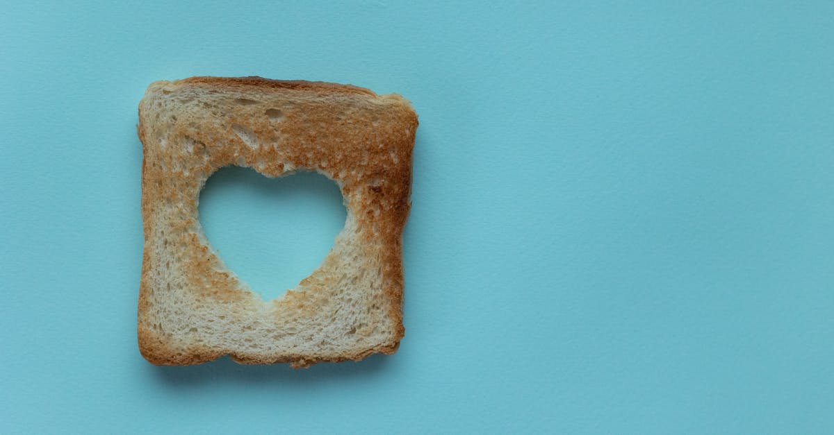 Butter crunch French bread topping - Top view of piece of white bread with cut heart on blue background Butter crunch French bread topping - Top view of piece of white bread with cut heart on blue background