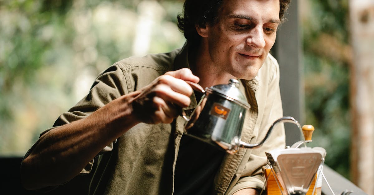 Caffeine content of cold-brewed coffee: higher or lower than hot-brewed? - Positive man pouring water into filter