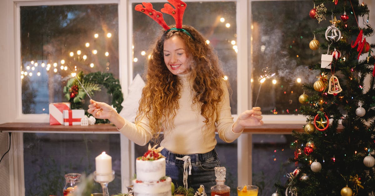 cake burns on bottom - Cheerful female in decorative deer horns with burning sparklers standing at table with tasty cake for New Year holiday at home cake burns on bottom - Cheerful female in decorative deer horns with burning sparklers standing at table with tasty cake for New Year holiday at home
