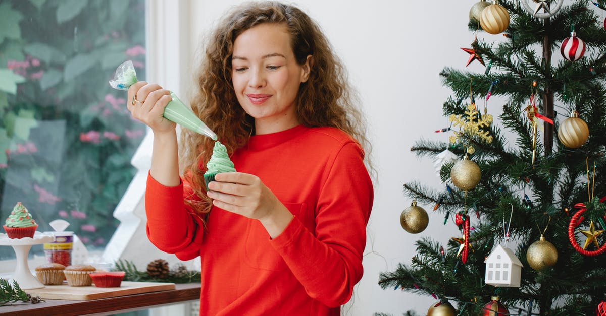 Can a failed cupcake be incorpated into a new cupcake? - Cheerful female with pastry bag piping green cream on cupcake while sitting near window and decorated fir during Christmas holiday preparation Can a failed cupcake be incorpated into a new cupcake? - Cheerful female with pastry bag piping green cream on cupcake while sitting near window and decorated fir during Christmas holiday preparation