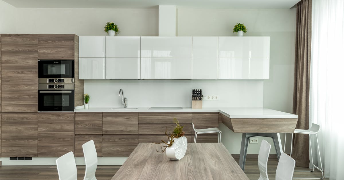 Can a large number of eggs be scrambled in a pot? - Modern open plan kitchen with white glossy and wooden cabinets and dining table with white chairs near in light apartment Can a large number of eggs be scrambled in a pot? - Modern open plan kitchen with white glossy and wooden cabinets and dining table with white chairs near in light apartment