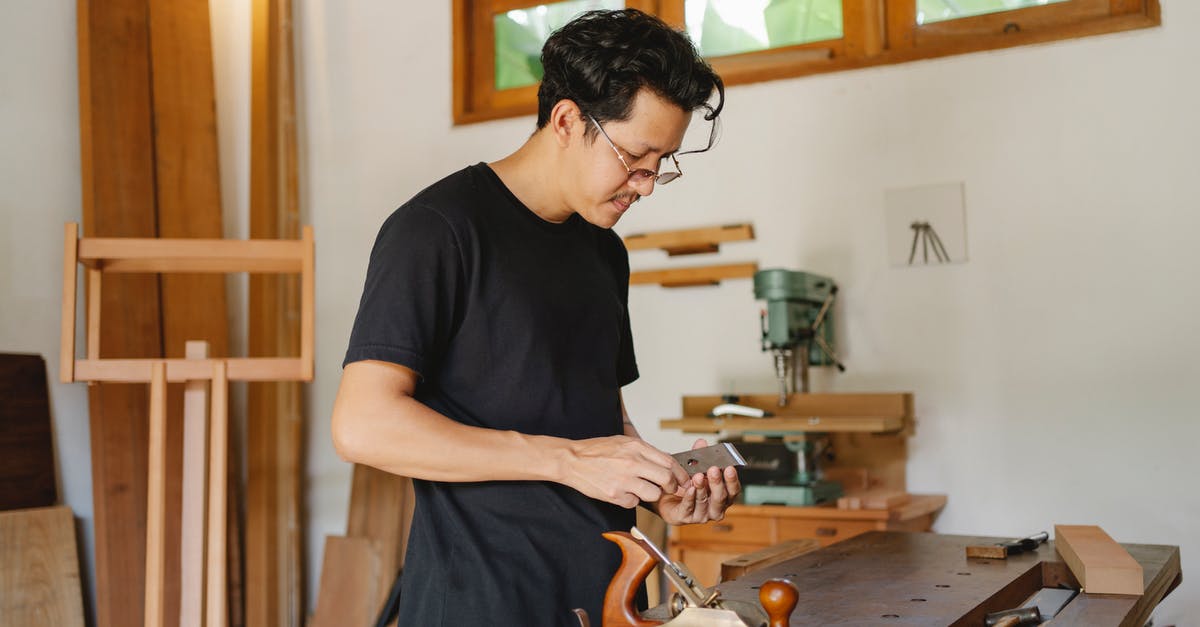 Can bad honing technique spoil a knife? - Side view of concentrated male craftsman standing with planer knives at wooden workbench with jointer during work in professional studio Can bad honing technique spoil a knife? - Side view of concentrated male craftsman standing with planer knives at wooden workbench with jointer during work in professional studio
