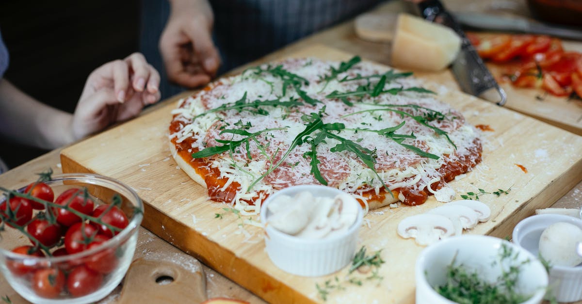 Can fresh basil cause tomato sauce spoilage? - Unrecognizable women and unbaked pizza with cheese and herbs on chopping board on table in kitchen Can fresh basil cause tomato sauce spoilage? - Unrecognizable women and unbaked pizza with cheese and herbs on chopping board on table in kitchen