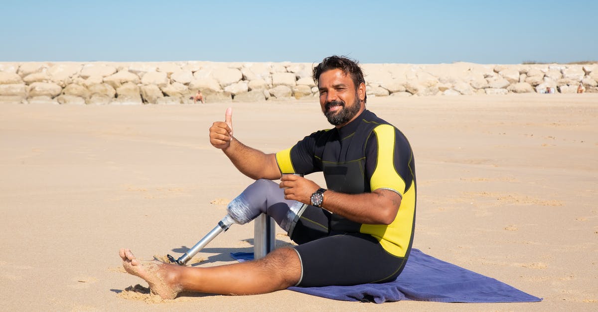 Can I carve up a suckling pig like you would an adult pig? - Side view full length handsome ethnic man with leg prosthesis resting on sandy seashore and showing thumb up gesture while looking at camera with smile Can I carve up a suckling pig like you would an adult pig? - Side view full length handsome ethnic man with leg prosthesis resting on sandy seashore and showing thumb up gesture while looking at camera with smile