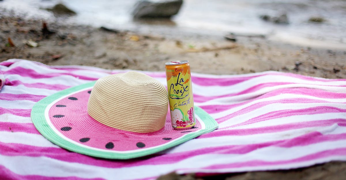 Can I dissolve mint in water and drink it? - Striped towel spread on sandy beach with straw hat and juice can