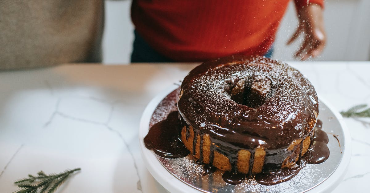 Can I make a sponge cake without sugar? - From above of crop anonymous parent with black kid pouring powdered sugar on Christmas sponge cake with chocolate glaze