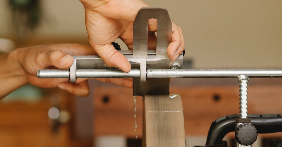Can I sharpen a knife with sandpaper? - Side view of unrecognizable craftsman sitting at sharpening machine with metal stick while grinding knife in professional studio on blurred background Can I sharpen a knife with sandpaper? - Side view of unrecognizable craftsman sitting at sharpening machine with metal stick while grinding knife in professional studio on blurred background