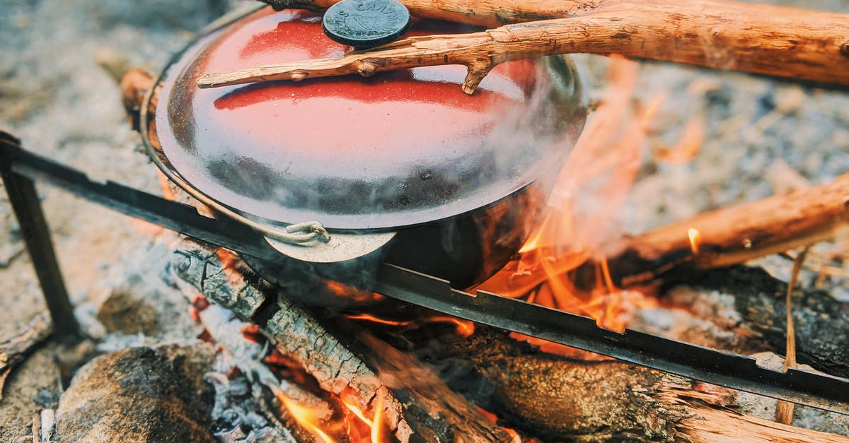 Can I stack pots while cooking? - Hot pot on metal racks placed on burning bonfire with log while cooking during camping in woods on blurred background Can I stack pots while cooking? - Hot pot on metal racks placed on burning bonfire with log while cooking during camping in woods on blurred background