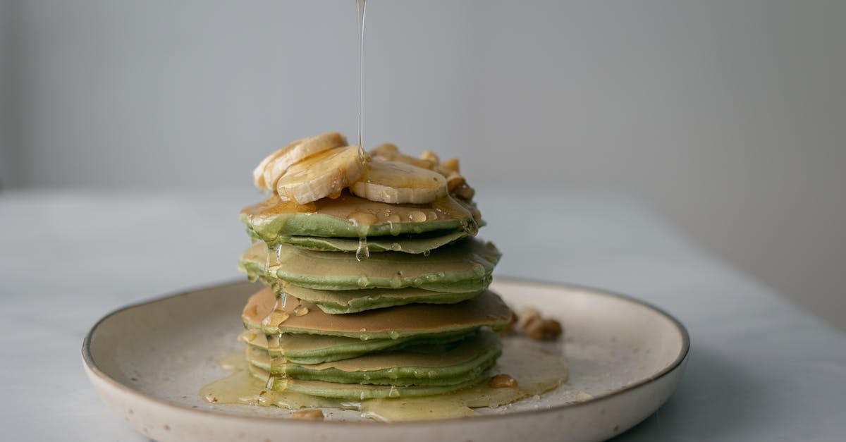Can I substitute Molasses for Honey in Baking Recipes? - Unrecognizable person pouring honey on stack of appetizing green pancakes topped with bananas and walnuts and served on plate on table Can I substitute Molasses for Honey in Baking Recipes? - Unrecognizable person pouring honey on stack of appetizing green pancakes topped with bananas and walnuts and served on plate on table