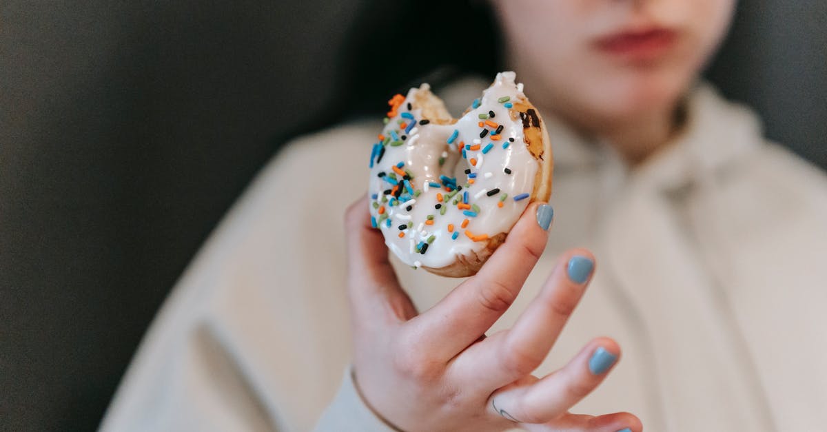 Can I use a flavored liqueur to make vanilla extract? - Crop blurred female wearing comfy loose clothes chewing and showing bitten tasty doughnut