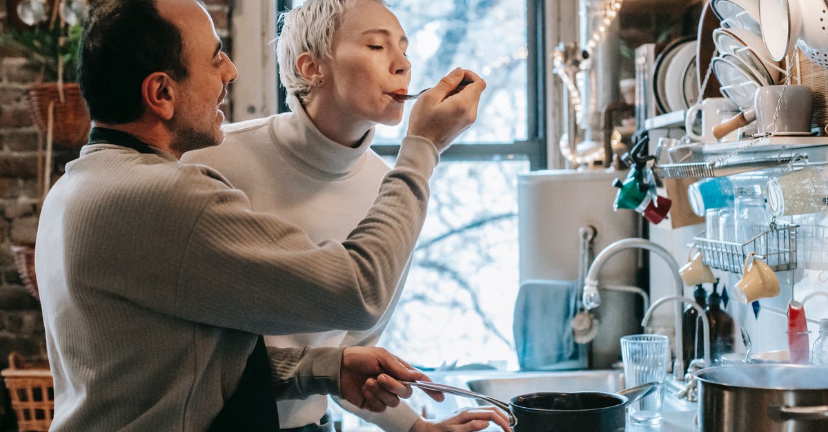 can Tilapia replace salmon in recipes and taste good? - Side view of content ethnic man in casual clothes and apron feeding happy wife while preparing delicious dinner at stove in kitchen